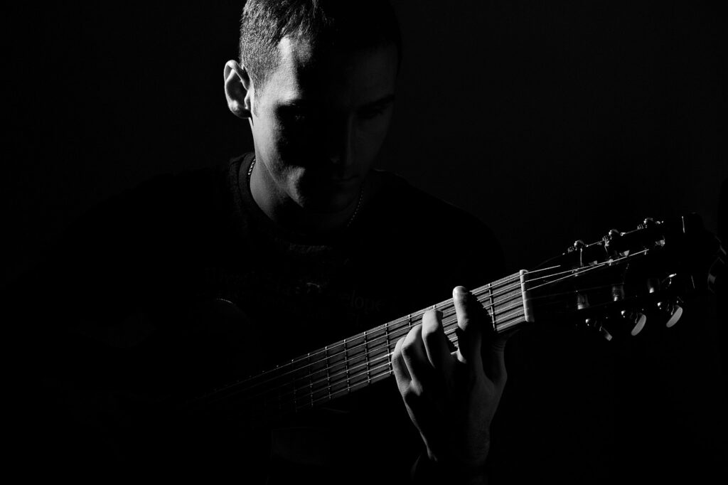 persona tocando la guitarra, foto en blanco y negro
