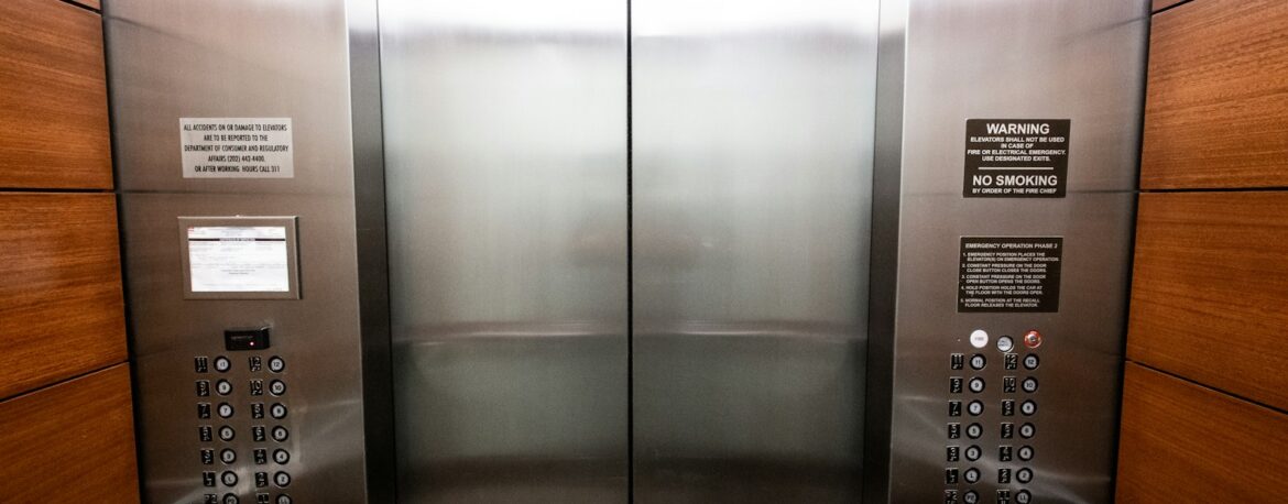 Interior de un ascensor de oficina con puertas metálicas cerradas