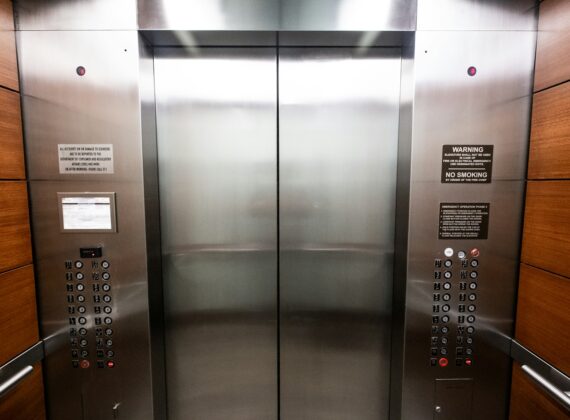 Interior de un ascensor de oficina con puertas metálicas cerradas