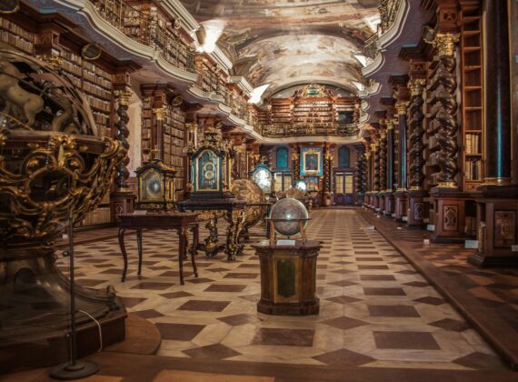Sala barroca de una biblioteca histórica de Praga con estanterías de libros antiguos y globos terráqueos
