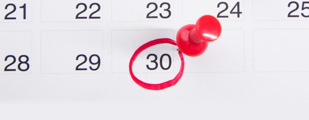 Calendario con una fecha rodeada con un círculo rojo y una chincheta roja al lado