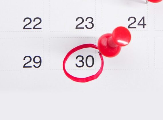 Calendario con una fecha rodeada con un círculo rojo y una chincheta roja al lado