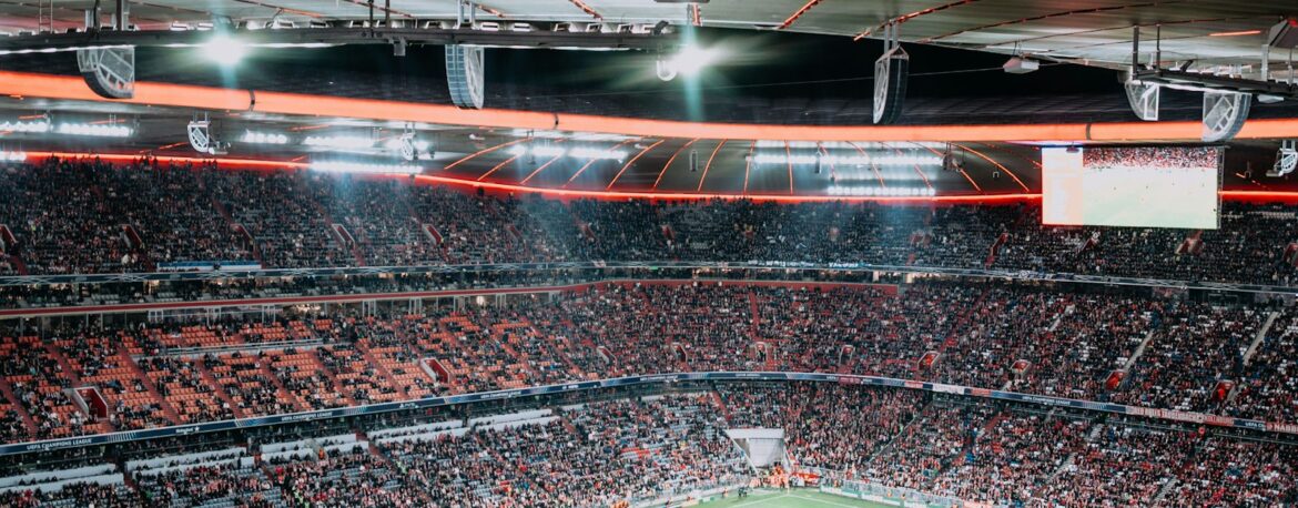 Estadio de fútbol lleno de público durante un partido nocturno con los focos encendidos