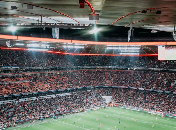 Estadio de fútbol lleno de público durante un partido nocturno con los focos encendidos