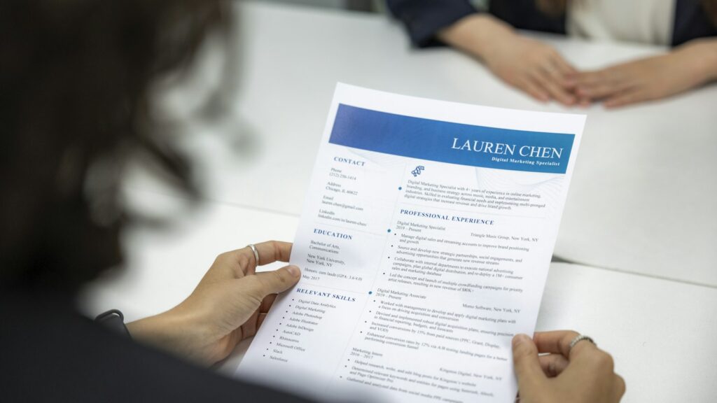 Persona leyendo un currículum impreso sobre una mesa de trabajo