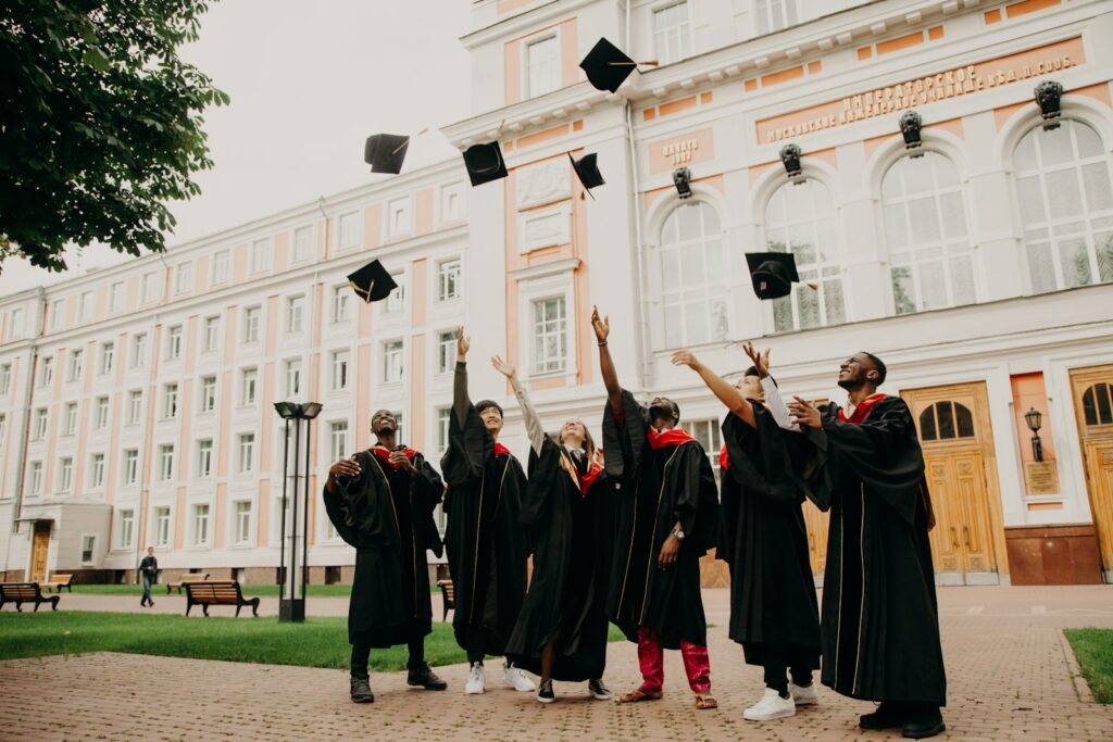Estudiantes internacionales con toga y birrete lanzando sus gorras al aire durante su ceremonia de graduación