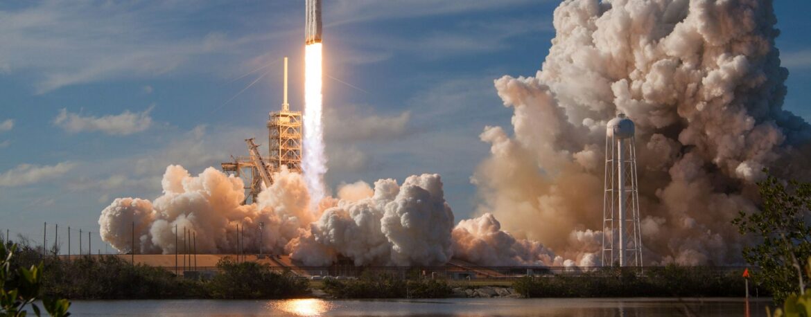 Lanzamiento de un cohete Falcon Heavy con una gran nube de humo junto al agua