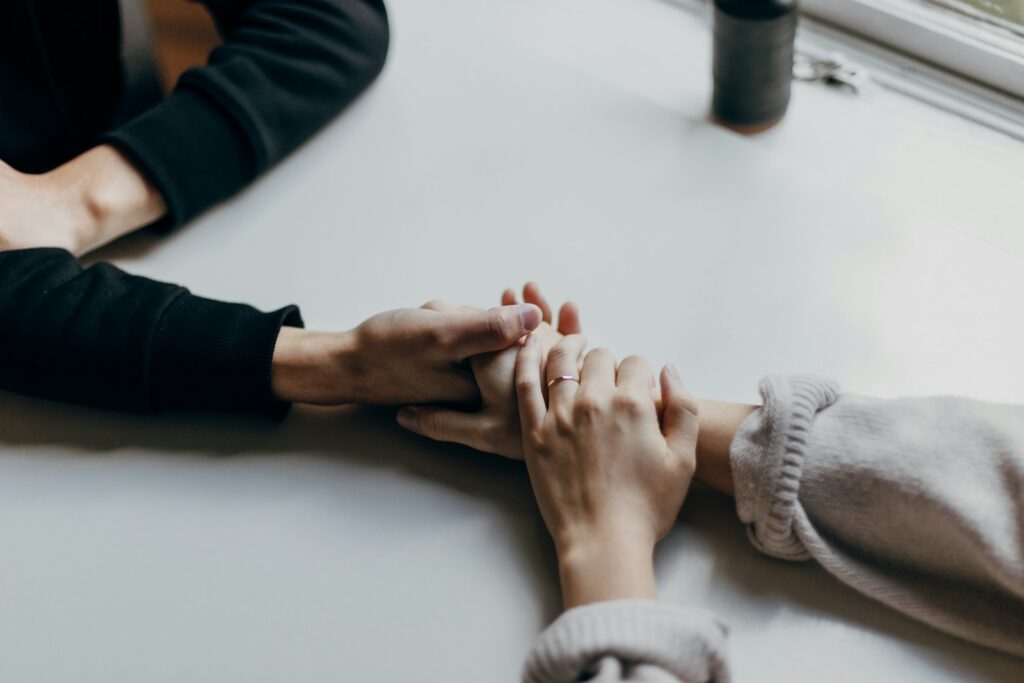 Dos personas se cogen de las manos sobre una mesa en un gesto de apoyo