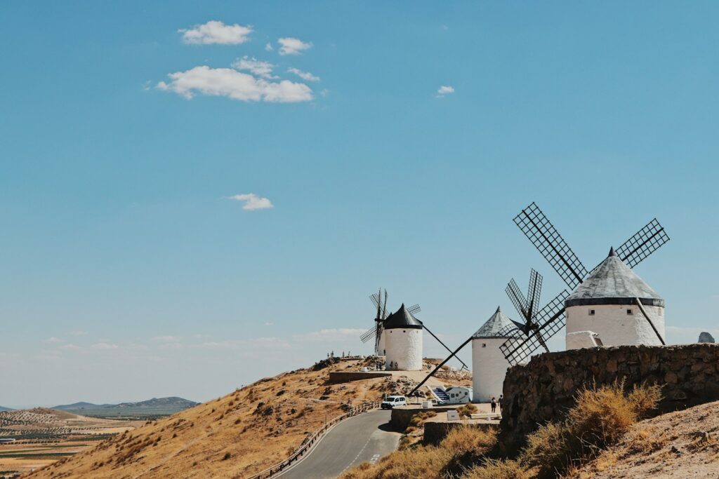 Molinos de viento blancos sobre el cerro de Consuegra en La Mancha bajo un cielo azul