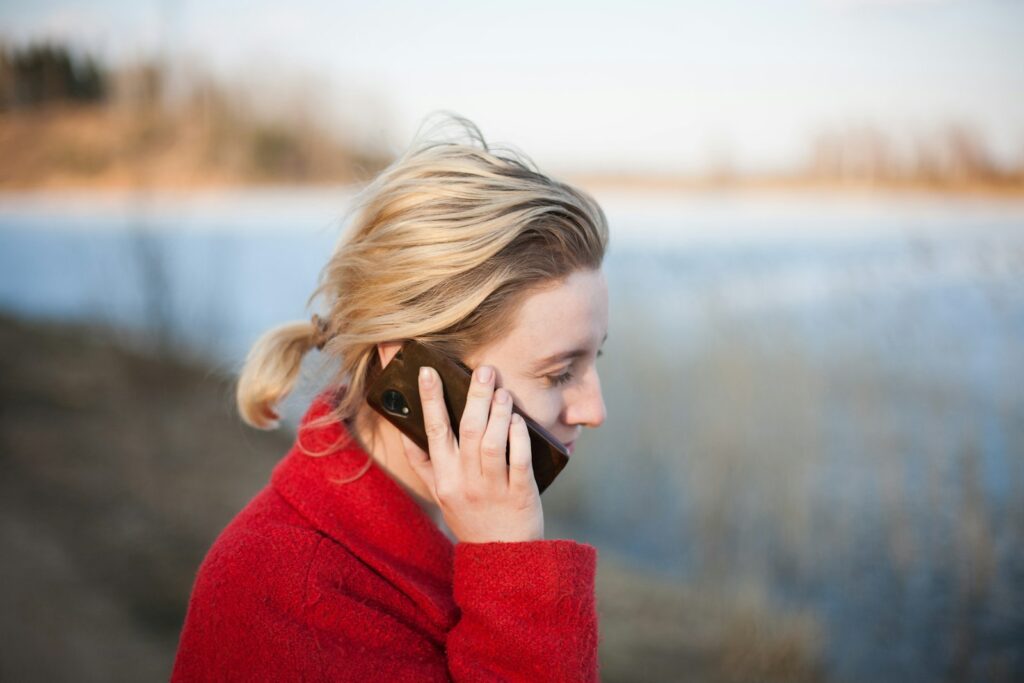 Mujer con jersey rojo hablando por teléfono móvil al aire libre