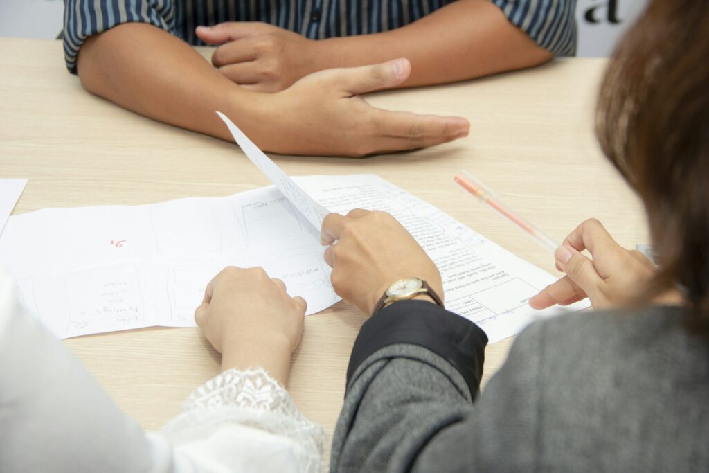 Dos personas revisan documentos impresos sobre una mesa de reuniones