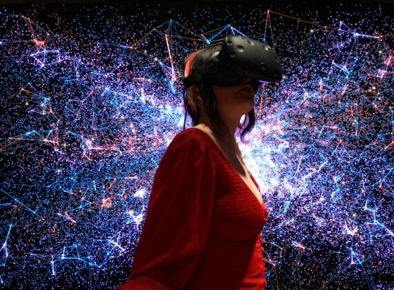 Mujer con gafas de realidad virtual rodeada de una proyección de luces y partículas