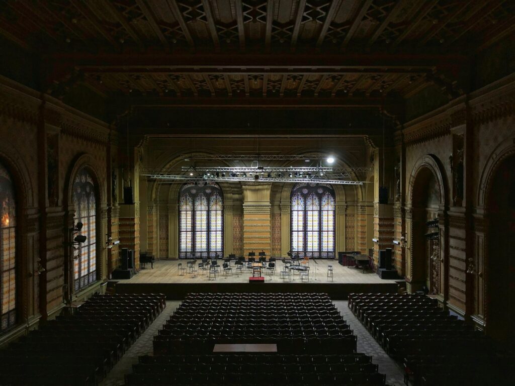 Interior de un teatro antiguo con el patio de butacas a oscuras y el escenario iluminado
